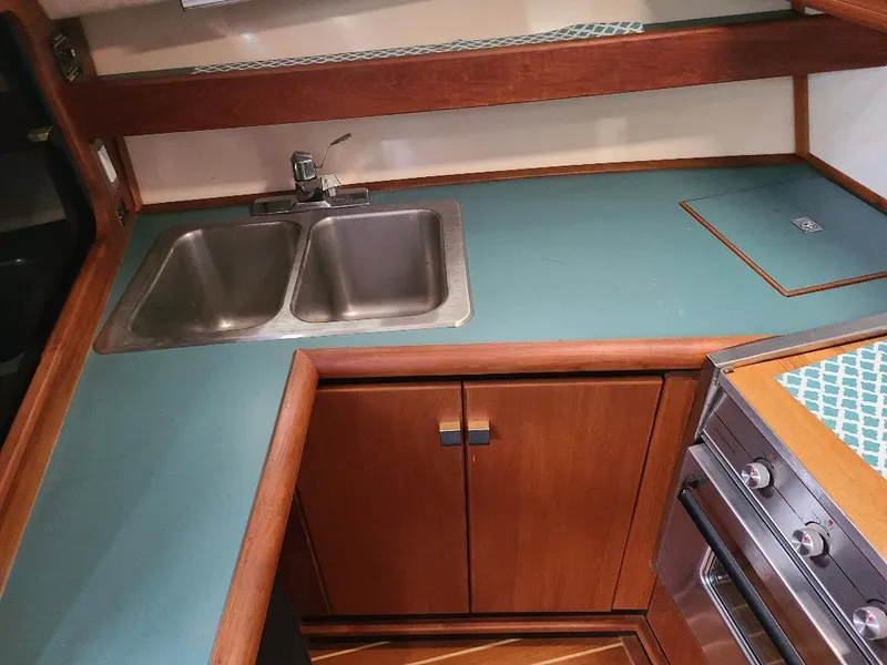 Slide: The Image of 1989 Bayliner 3255 Avanti kitchen with dual sink, teal countertop, and wooden cabinetry. - 10