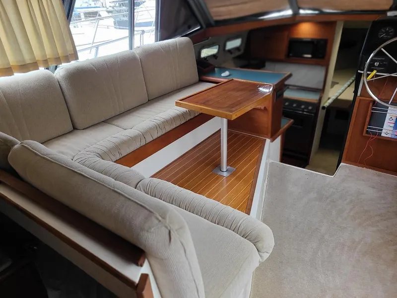 Slide: The Image of 1989 Bayliner 3255 Avanti interior with beige seating, wooden table, and helm station. - 15