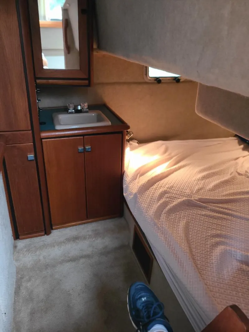 Slide: The Image of 1989 Bayliner 3255 Avanti cabin interior with bed, sink, and wooden cabinetry. - 27