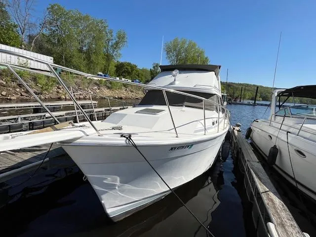 Slide: The Image of 1989 Bayliner 3255 Avanti docked at a marina on a sunny day. - 3