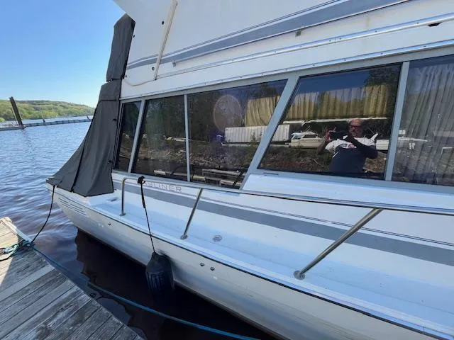 Slide: The Image of 1989 Bayliner 3255 Avanti docked by a lake with scenic background. - 7