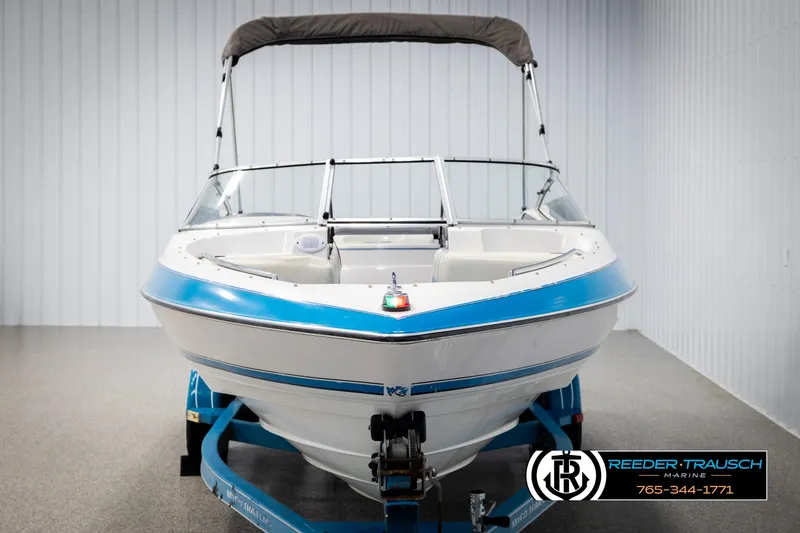 Slide: The Image of 1993 Excel 20SX boat with blue trim on a trailer in a showroom. - 8