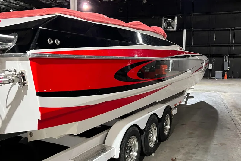 Slide: The Image of 2004 Spectre 36 Cat powerboat with red and black design on a triple-axle trailer. - 28
