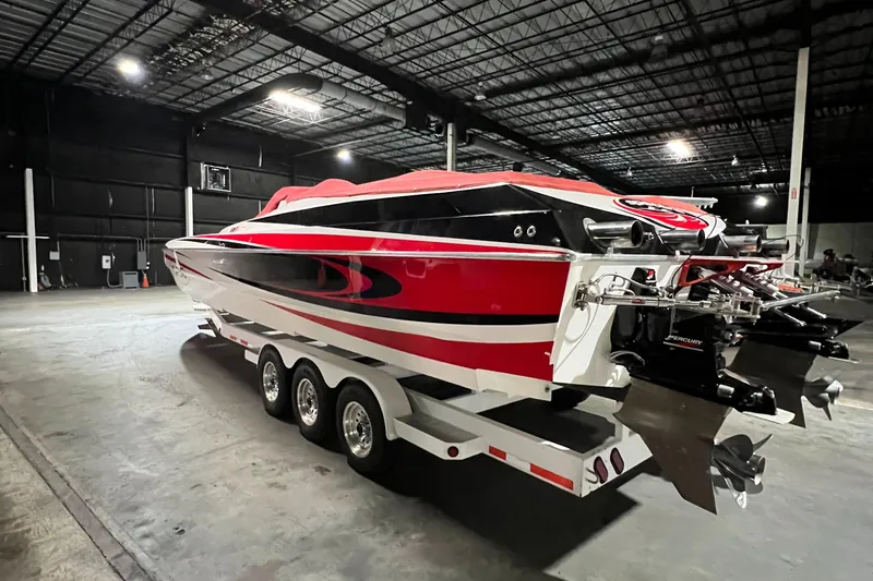 Slide: The Image of 2004 Spectre 36 Cat powerboat with red and black design on a triple-axle trailer in a warehouse. - 29