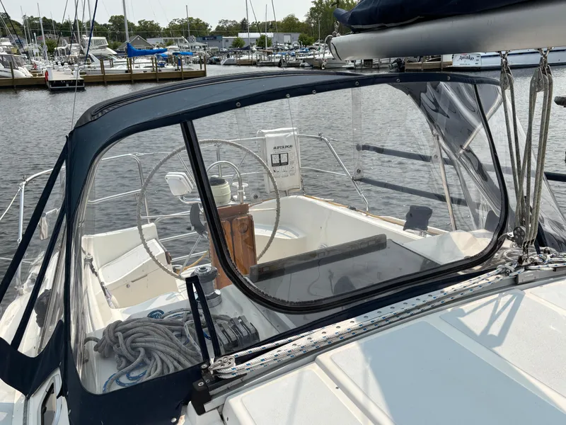 Slide: The Image of 1990 Hunter 33.5 sailboat cockpit with steering wheel, ropes, and marina view. - 19