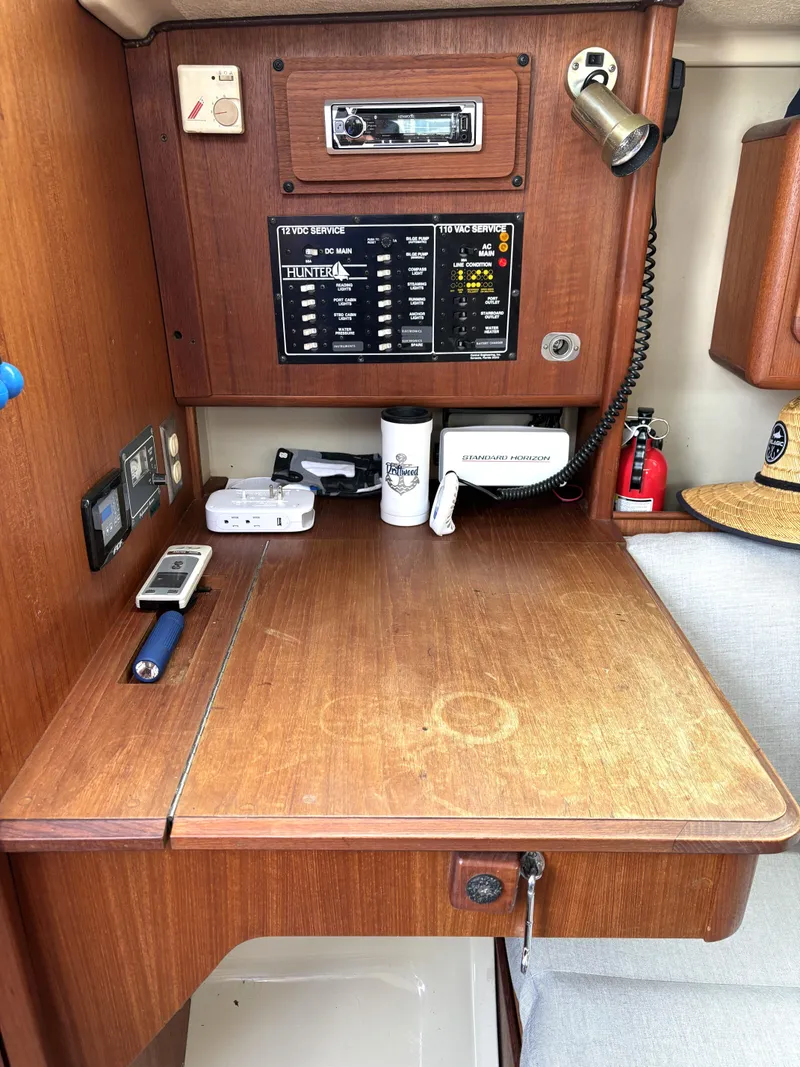 Slide: The Image of 1990 Hunter 33.5 sailboat navigation station with control panel, radio, and wooden desk. - 39