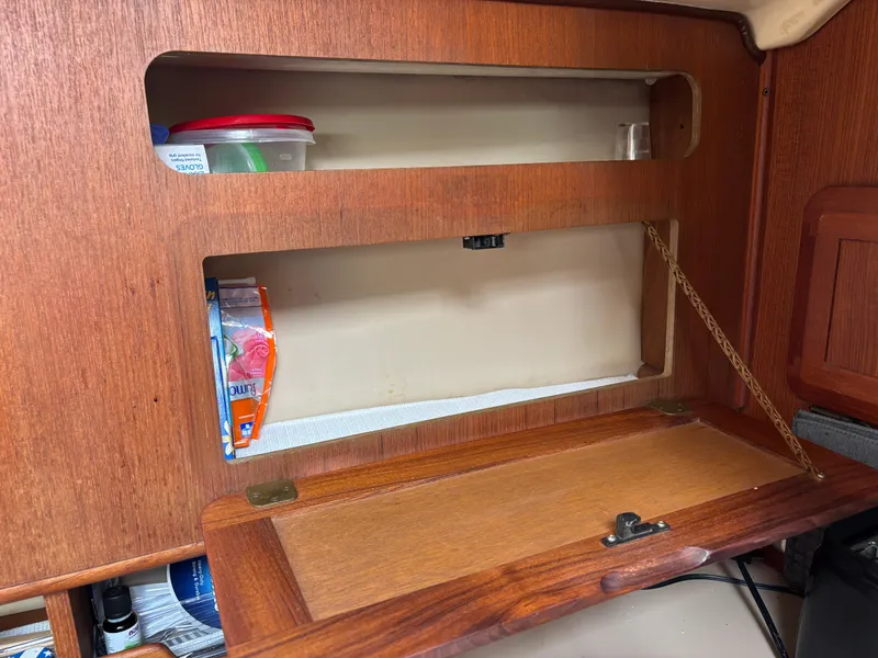 Slide: The Image of Wooden storage compartment in a 1990 Hunter 33.5 boat interior, with shelves and items. - 49