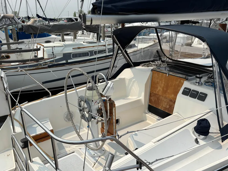 Slide: The Image of 1990 Hunter 33.5 sailboat cockpit with steering wheel, docked at marina. - 8