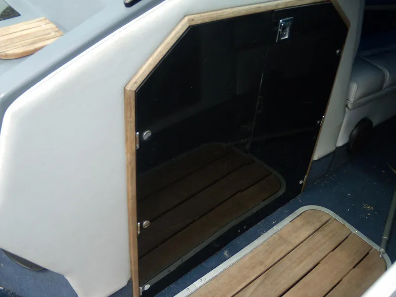 Slide: The Image of 1989 Chaparral 2300 SX Sport boat interior with wooden accents and black panel door. - 11