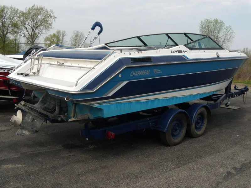Slide: The Image of 1989 Chaparral 2300 SX Sport boat on trailer, blue and white design, parked outdoors. - 3