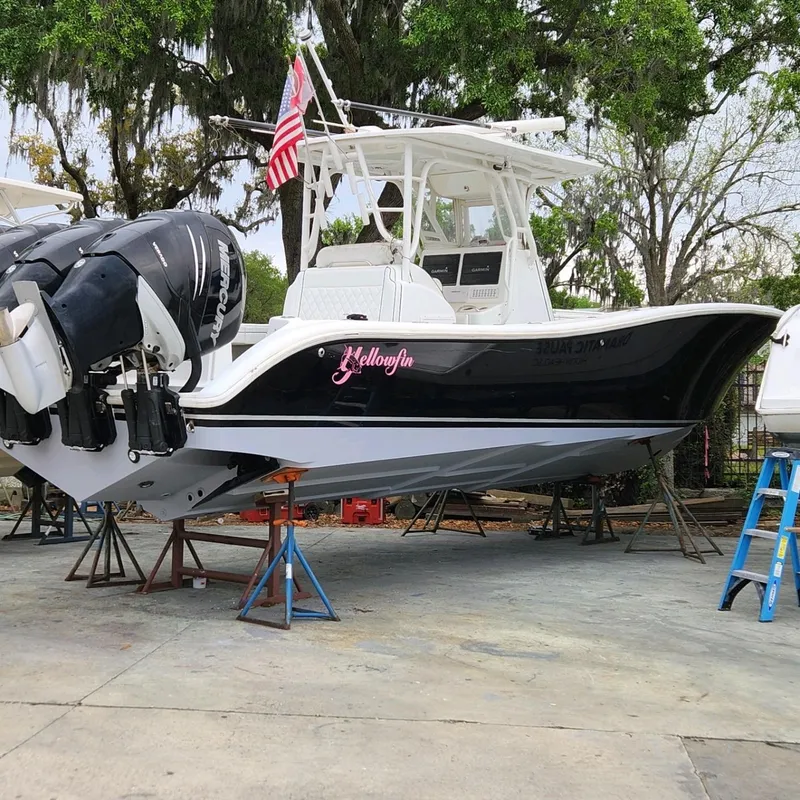 Slide: The Image of 2007 Yellowfin 36 boat on stands, with twin outboard engines, American flag, and lush greenery. - 5