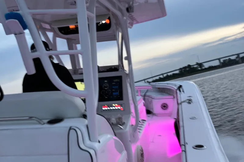 Slide: The Image of 2007 Yellowfin 36 boat with illuminated pink interior lights, cruising on water at dusk. - 7
