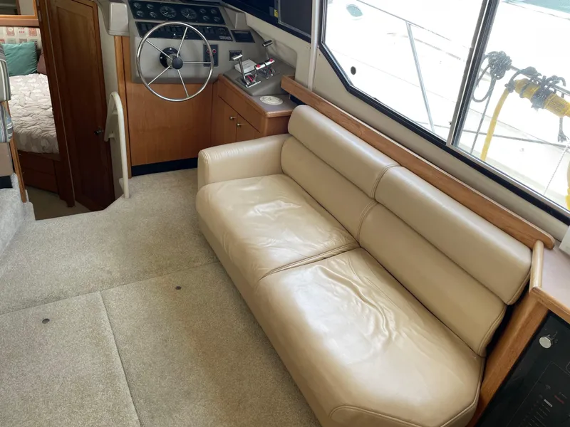 Slide: The Image of 1998 Bayliner 4087 Aft Cabin Motoryacht interior with helm, beige sofa, and cabin view. - 12