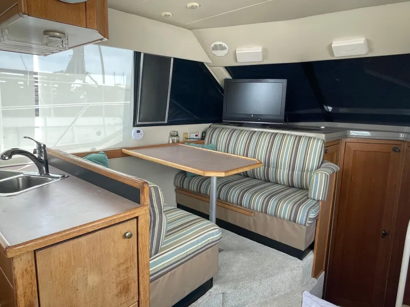 Slide: The Image of 1998 Bayliner 4087 Aft Cabin Motoryacht interior with striped seating and compact dining area. - 17