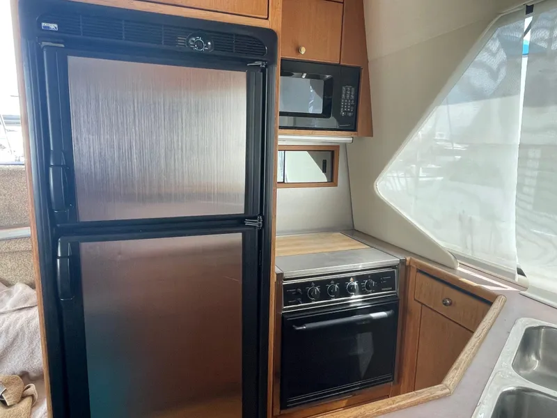 Slide: The Image of 1998 Bayliner 4087 yacht kitchen with fridge, microwave, oven, and sink. - 18