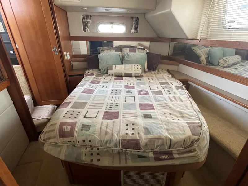 Slide: The Image of 1998 Bayliner 4087 Aft Cabin Motoryacht bedroom with patterned bedding and wooden accents. - 20