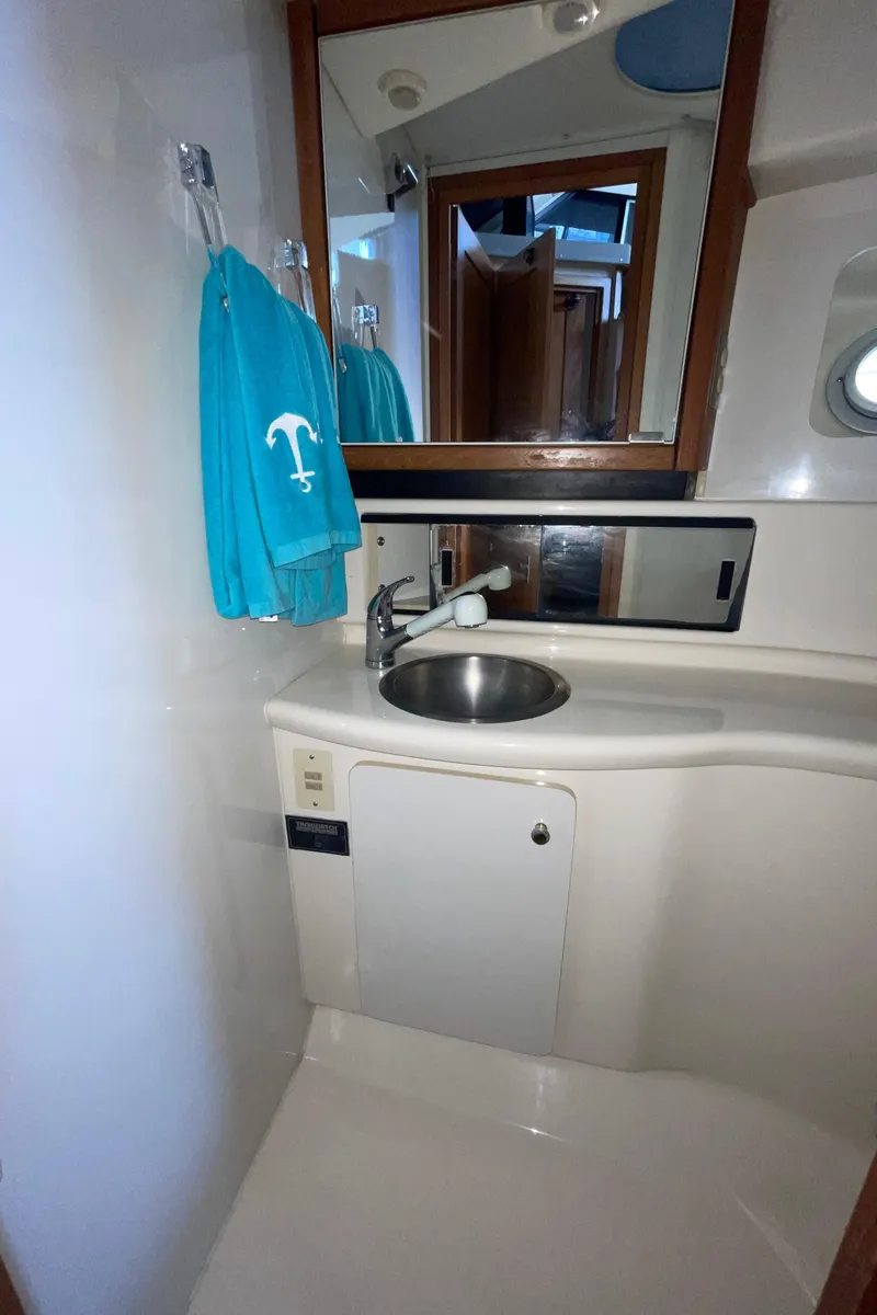Slide: The Image of 1998 Bayliner 4087 Aft Cabin Motoryacht bathroom with sink, mirror, and teal towels. - 34