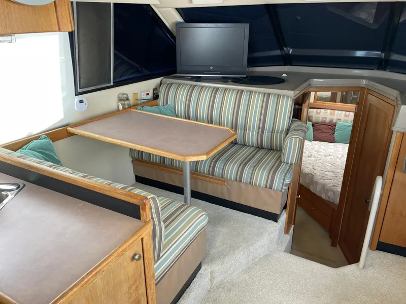 Slide: The Image of 1998 Bayliner 4087 Aft Cabin Motoryacht interior with striped seating, table, and TV. - 9