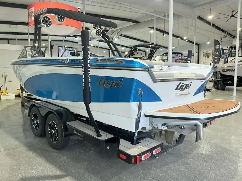 Slide: The Image of 2019 Tigé R23 boat in showroom, blue and white design, on a trailer. - 2