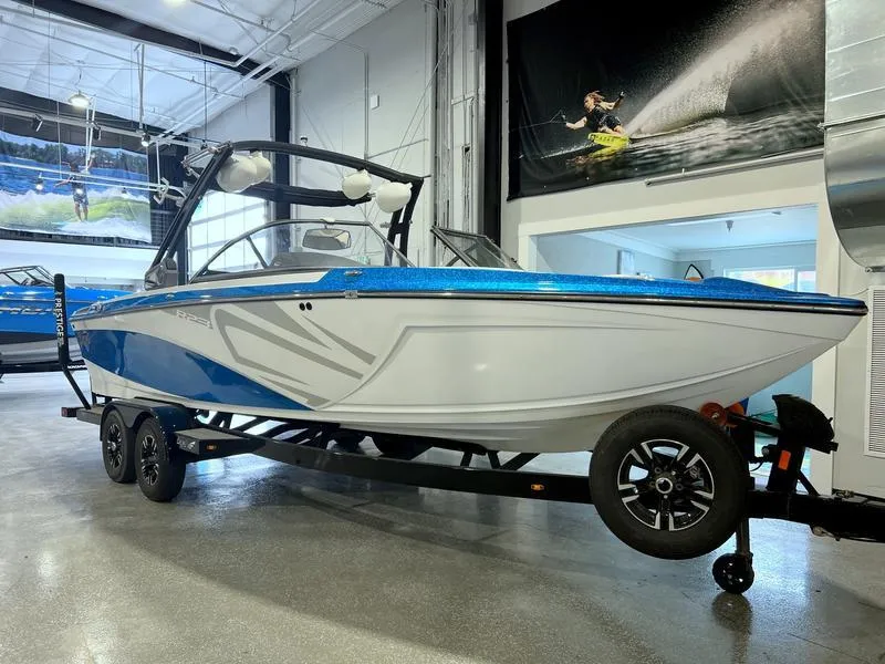 Slide: The Image of 2019 Tigé R23 boat in showroom, blue and white design, on trailer. - 5