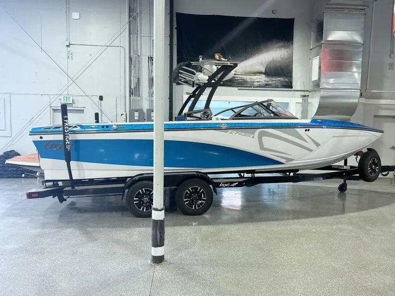 Slide: The Image of 2019 Tigé R23 boat in showroom, blue and white design on trailer. - 7