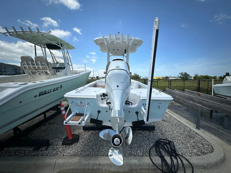Slide: The Image of 2025 Sea Pro 230 Bay boat with outboard motor, parked on gravel under clear sky. - 2
