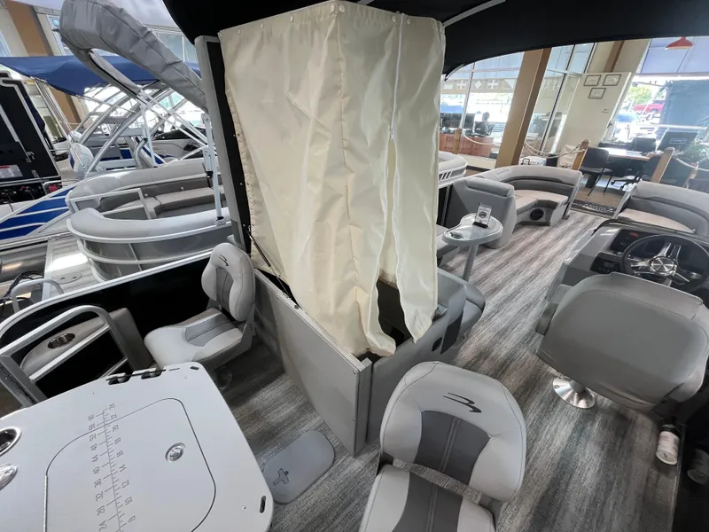 Slide: The Image of 2025 Bennington 22SXSAPG pontoon boat interior with seating, table, and privacy curtain. - 15