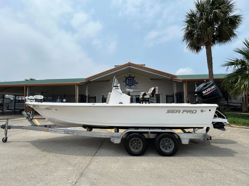 Slide: The Image of 2020 Sea Pro 228 Bay boat on trailer, parked outdoors near a building and palm trees. - 0