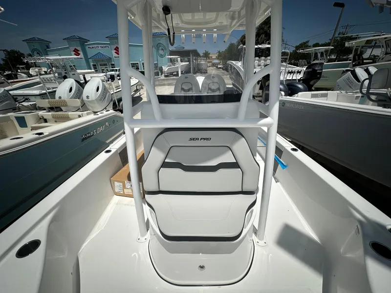 Slide: The Image of 2025 Sea Pro 250 Bay boat interior with seating and console, displayed at a marina. - 11
