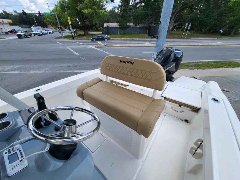 Slide: The Image of 2024 Bayliner Trophy T22CC boat interior with steering wheel and seating, parked near a road. - 11