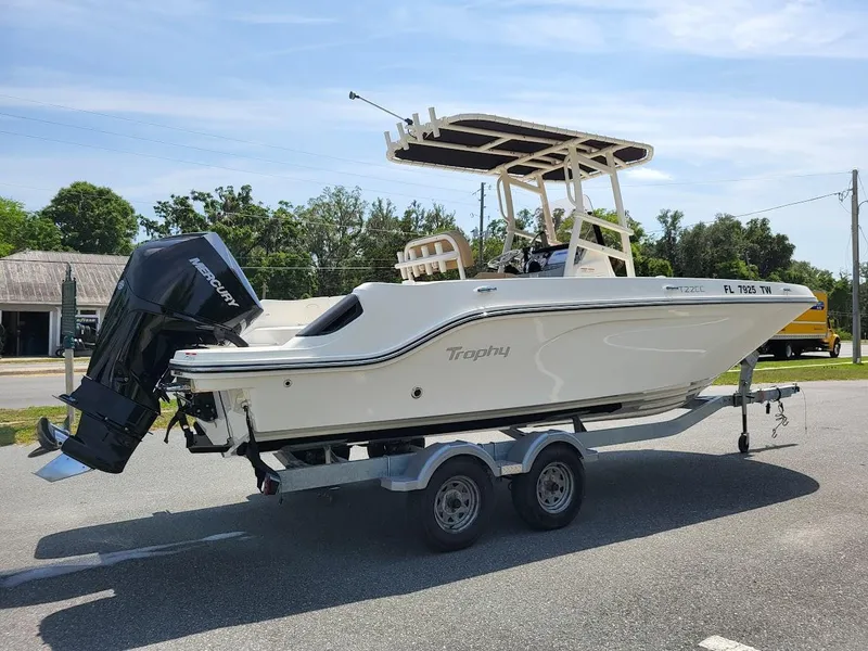 Slide: The Image of 2024 Bayliner Trophy T22CC boat on trailer, parked outdoors, side view. - 2