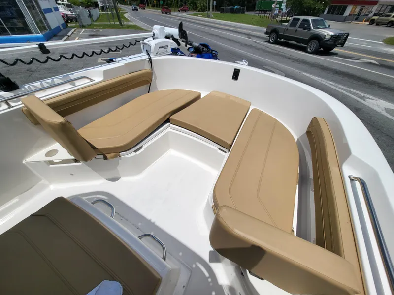 Slide: The Image of 2024 Bayliner Trophy T22CC boat with tan seating, docked near a road. - 8