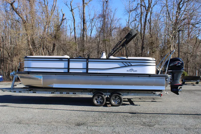 The Image of 2025 SunCatcher Select 324RC pontoon boat on trailer, parked in wooded area. - 0