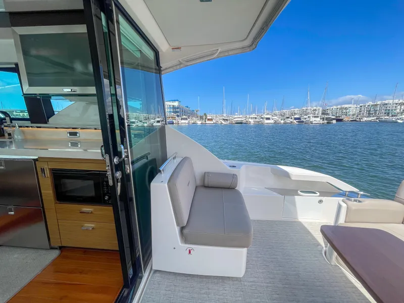 Slide: The Image of 2017 Tiara Yachts 44 Coupe interior with marina view, featuring seating and kitchenette. - 18