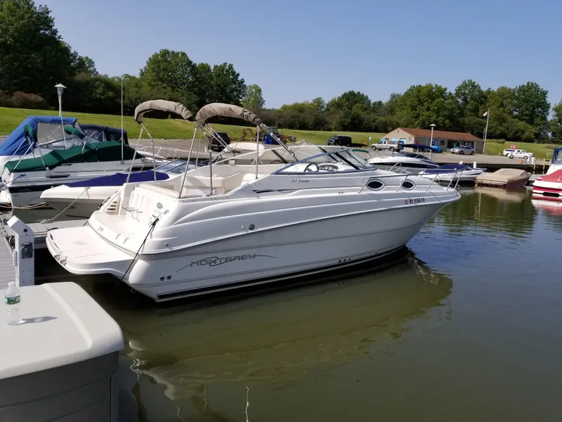 Slide: The Image of 2001 Monterey 262 Cruiser docked, featuring sleek design and enclosed cabin. - 4