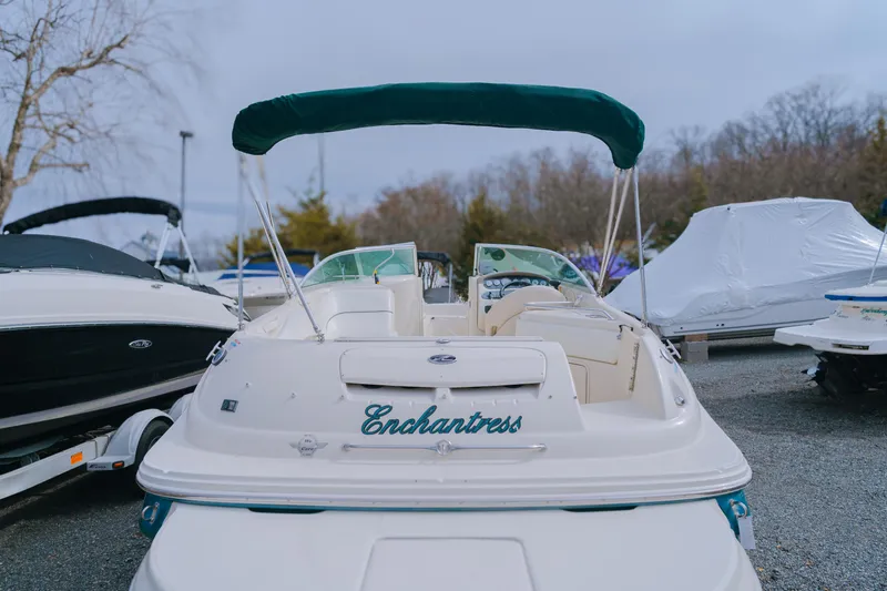 Slide: The Image of 2003 Sea Ray 240 Sundeck boat with green canopy, named "Enchantress," parked outdoors. - 3