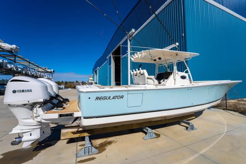 Slide: The Image of 2019 Regulator 34 boat with Yamaha engines, docked near a blue building. - 3