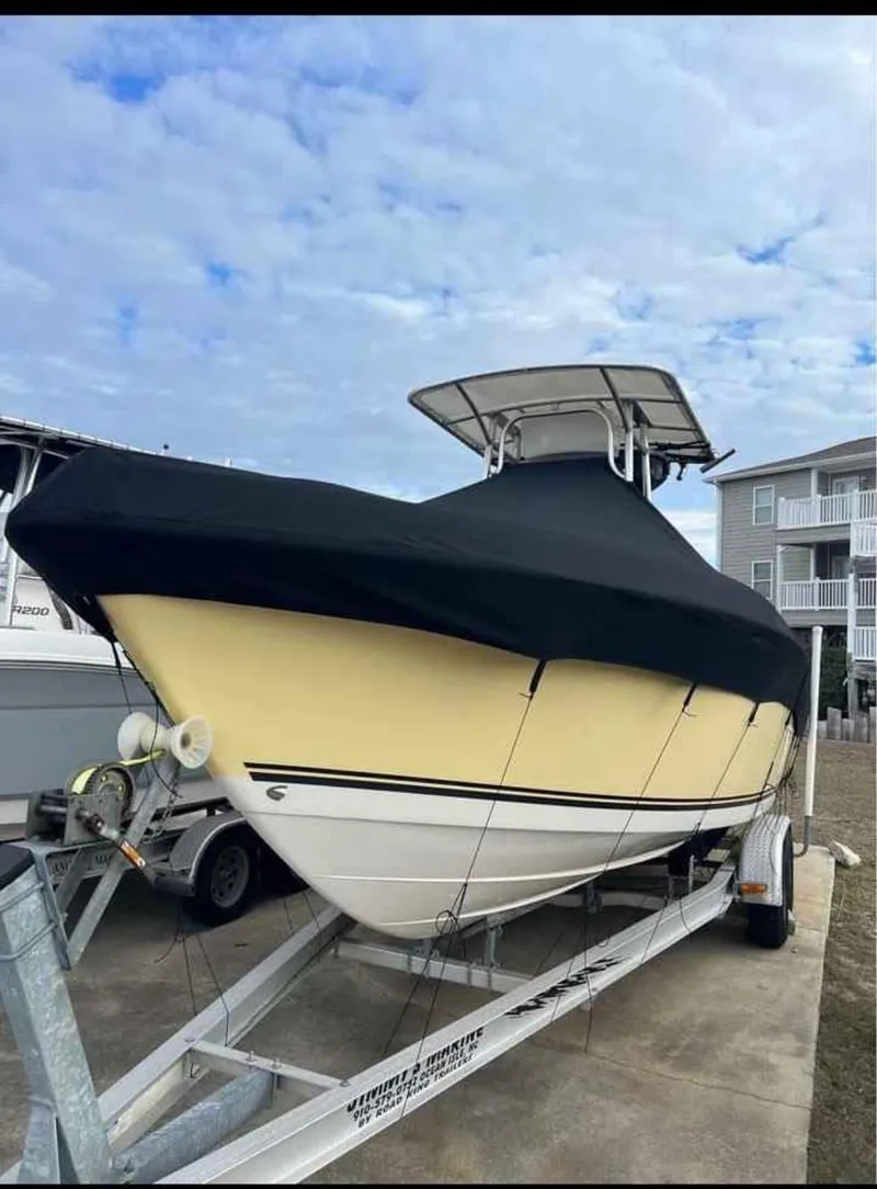 Slide: The Image of 2008 Clearwater 2500 boat on trailer, covered, with cloudy sky background. - 2
