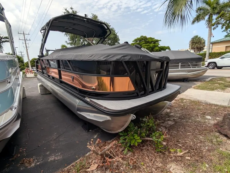 Slide: The Image of 2026 Trifecta 23UL SS ARCH pontoon boat with sleek design, parked outdoors. - 3