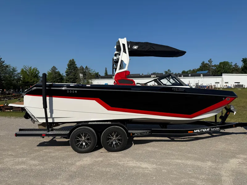 Slide: The Image of 2025 Nautique Super Air Nautique GS22 boat on trailer, black and red design, outdoor setting. - 6