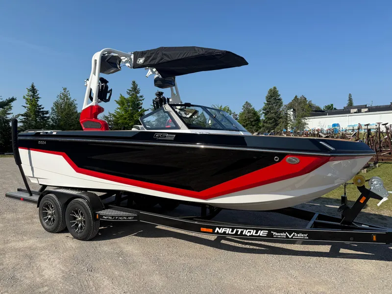 Slide: The Image of 2025 Nautique Super Air Nautique GS22 boat on trailer, black and red design, parked outdoors. - 7