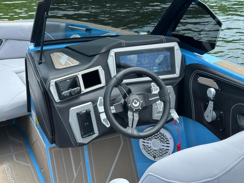Slide: The Image of 2025 Centurion NV233 boat dashboard with modern controls and steering wheel on a lake. - 10
