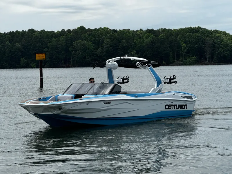 Slide: The Image of 2025 Centurion NV233 boat cruising on a lake with forested shoreline. - 4