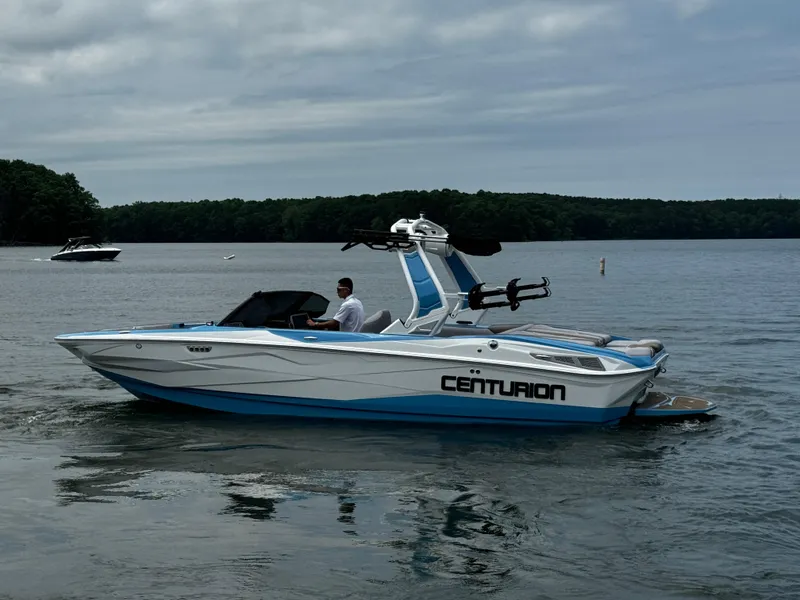 Slide: The Image of 2025 Centurion NV233 boat on a calm lake with a cloudy sky. - 7