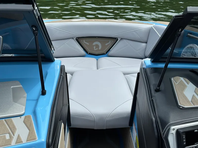 Slide: The Image of 2025 Centurion NV233 boat interior with blue accents and cushioned seating, on a calm water backdrop. - 8