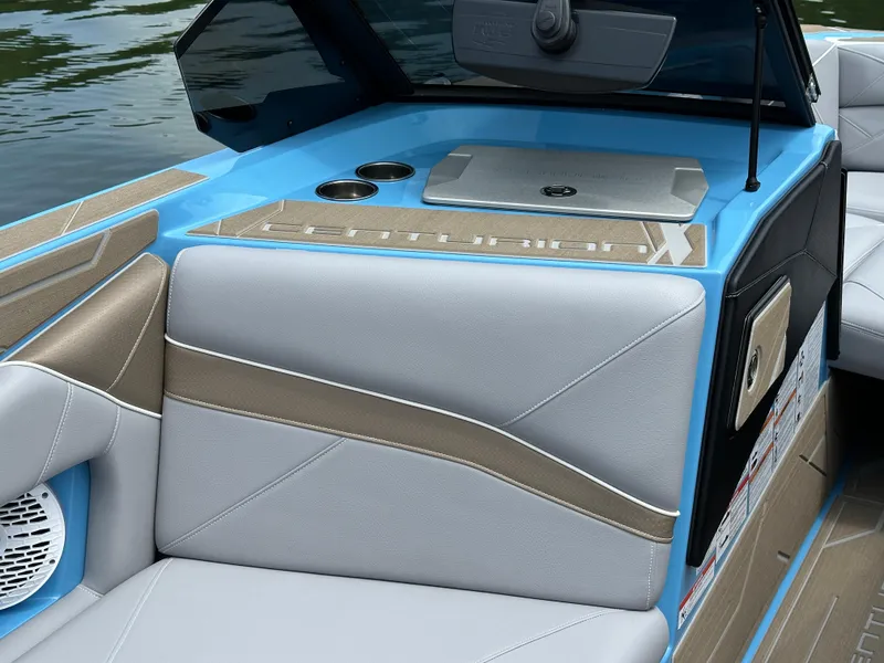Slide: The Image of 2025 Centurion NV233 boat interior with blue and beige seating, cup holders, and sleek design. - 9