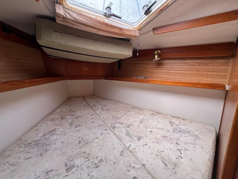 Slide: The Image of 1995 Catalina 400 sailboat interior cabin with bed, wooden accents, and overhead window. - 23