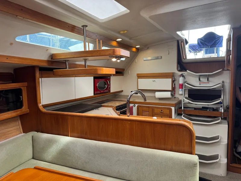 Slide: The Image of Interior of a 1995 Catalina 400 sailboat, featuring a cozy kitchen and seating area. - 8