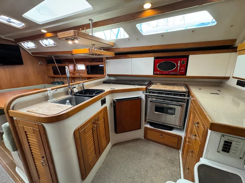 Slide: The Image of Interior of 1995 Catalina 400 yacht kitchen with modern appliances and wooden cabinetry. - 9