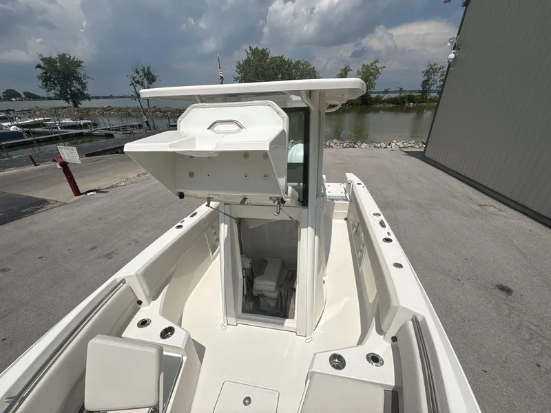 Slide: The Image of 2025 Sailfish 232 CC boat with open storage compartment, docked near a marina under cloudy skies. - 15